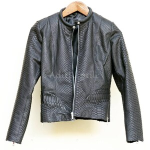 Könnte beinhalten: Eine schwarze Jacke mit texturiertem Schlangenledermuster, ausgestattet mit einem Stehkragen, einem durchgehenden silberfarbenen Reißverschluss und langen Ärmeln. Das Kleidungsstück hängt an einem Holzkleiderbügel und hat ein schwarzes Innenfutter.