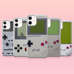 May include: Five clear phone cases with retro Game Boy designs. Each case features a different design, including the classic Nintendo Game Boy layout, a Tetris game screen, and the Game Boy logo. The cases are arranged against a pink background.