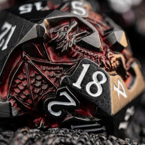 Peut inclure: Gros plan sur un dé polyédrique noir et rouge avec un motif de dragon. Le dé présente des chiffres blancs et un relief de dragon détaillé. Le dragon est rouge et le dé a un bord doré métallique.