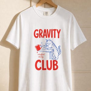 Gravity Club Cat T-Shirt Funny Cat Knocking Coffee Mug Off Table Tee Two Color Cat Lover Graphic Tee Gift imagem 4