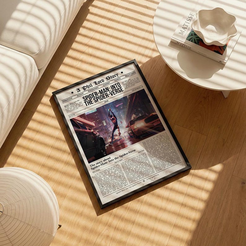 Puede incluir: Un p&oacute;ster enmarcado con dise&ntilde;o de peri&oacute;dico, con el titular "SPIDER-MAN: INTO THE SPIDER-VERSE". La imagen muestra a Spider-Man en una escena urbana. El marco negro est&aacute; sobre un suelo de madera. Aproximadamente 40 cm x 30 cm.