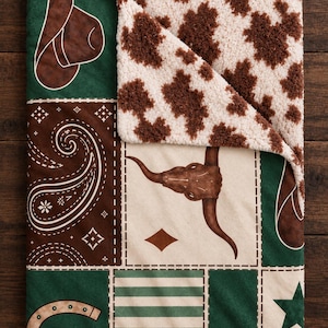 Könnte beinhalten: Eine rechteckige Wohndecke mit Patchwork-Design in Grün, Braun und Creme. Die Muster zeigen einen braunen Cowboyhut, ein weißes Paisley-Muster auf braunem Grund, einen Longhorn-Schädel, ein Hufeisen und einen Stern. Die Rückseite besteht aus braun-weißem Kuhfell-Sherpa.