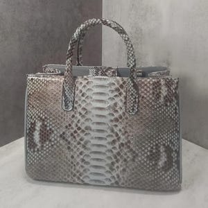 May include: A snakeskin-patterned handbag with a braided handle. The bag features a mix of brown, white, and gray tones, with a structured shape and a top handle. The interior is visible, and the bag appears to be made of leather.