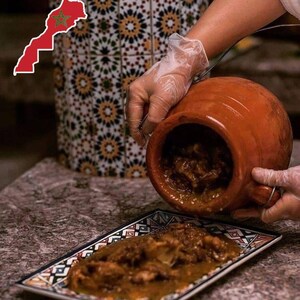 May include: A terracotta tagine pot is being used to serve a stew onto a rectangular plate with a geometric design. The stew is a rich brown color. The Moroccan flag is in the upper left corner.