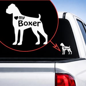 May include: A white vinyl decal featuring a Boxer dog silhouette with the words "my Boxer" and a heart symbol. The decal is shown on a vehicle window, with a close-up in a circular frame.