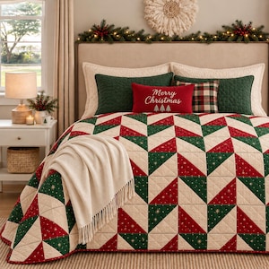 Può includere: Un letto con una trapunta dal motivo geometrico a triangoli rosso, verde e crema. Il letto include due federe verdi, un cuscino a quadri e un cuscino rettangolare rosso con il testo bianco Merry Christmas e tre piccoli alberi.