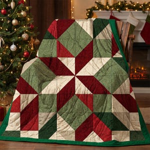May include: A quilted throw blanket featuring a geometric star pattern in shades of deep red, forest green, and cream. The fabric has a subtle mottled texture throughout, and the edges are finished with a solid dark green fabric binding.