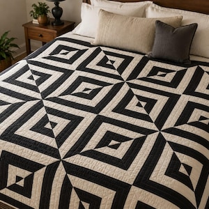 May include: A quilt featuring a repeating geometric pattern of black and off-white squares and triangles. The textile displays a high-contrast, angular design with visible stitching lines throughout the surface, covering the top of a bed.