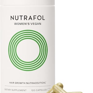 May include: A white cylindrical bottle of Nutrafol Women's Vegan hair growth nutraceutical dietary supplement. The bottle has a green circular design and the text "120 Capsules". Three capsules are in front of the bottle.