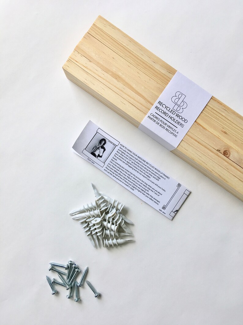 May include: A set of recycled wood record holders with instructions on how to hang them. The set includes screws, anchors, and a wooden frame.