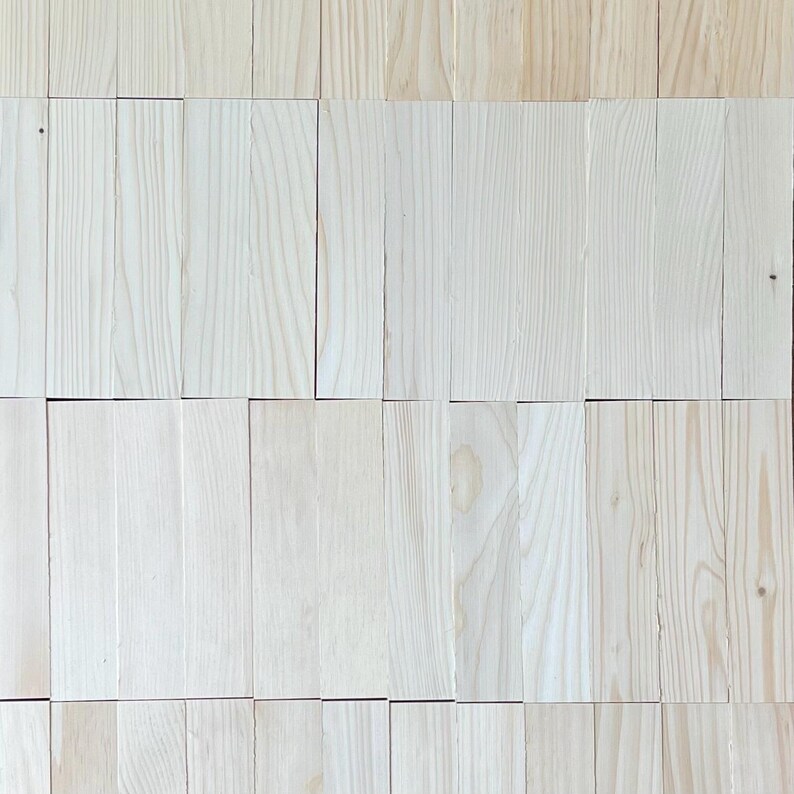 May include: A close-up of a wall made of light wood planks. The planks are arranged in a staggered pattern, creating a textured surface.