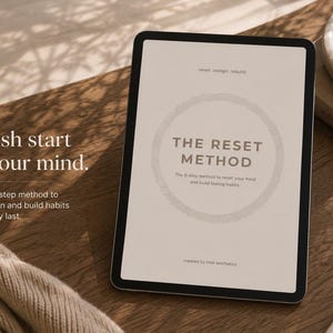 Könnte beinhalten: Ein digitales Tablet mit einem Dokument namens The Reset Method, das den Text A fresh start for your mind und A simple 6-step method to reset, realign and build habits that actually last zeigt, sowie ein weißer Stift auf einer Holzoberfläche.