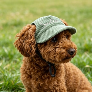 Puede incluir: Una gorra de béisbol de pana verde salvia con el nombre Sadie bordado en letra cursiva blanca en el panel frontal. La gorra incluye una correa de barbilla negra ajustable con un cierre de plástico para asegurar el sombrero en su lugar.