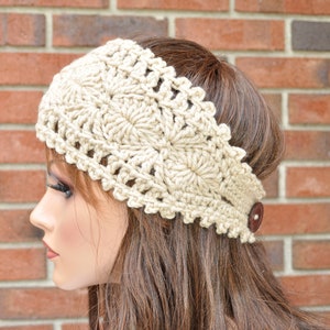 May include: A crocheted headband in a light beige color with a button on the side. The headband is made with a delicate, lacy pattern.