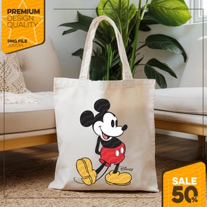 May include: Cream-colored tote bag featuring a smiling Mickey Mouse graphic in red, black, yellow, and white. The bag has long handles and the Disney logo. The image also includes text that says "Premium Design Quality" and "PNG File 300DPI".