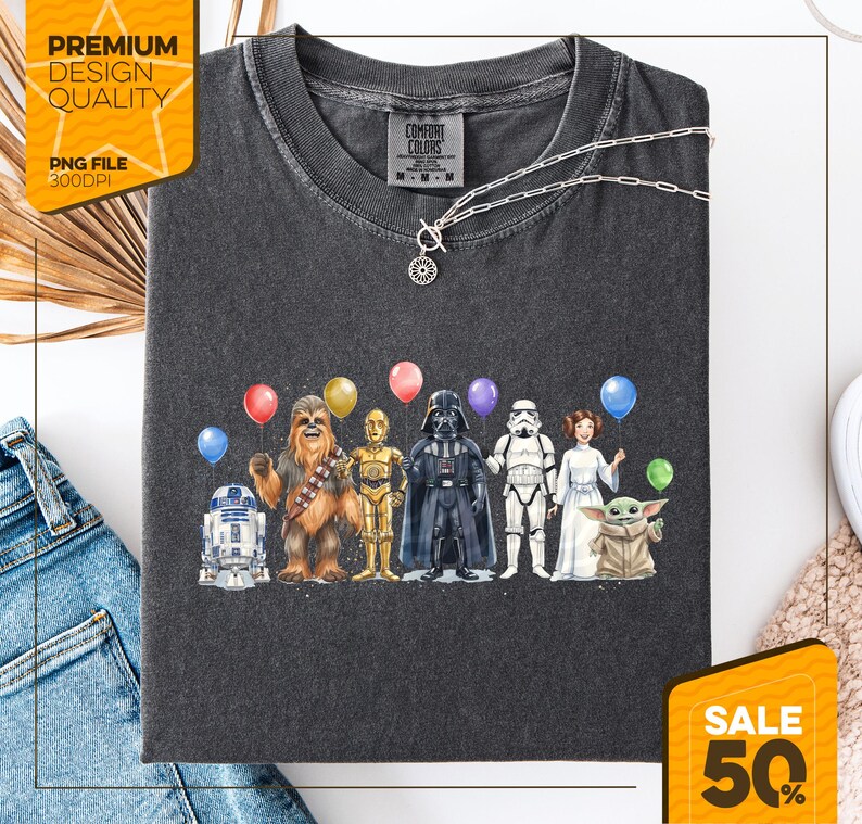 K&ouml;nnte beinhalten: Dunkelgraues Comfort Colors T-Shirt mit einer Star Wars-Charakteraufstellung mit Luftballons. Das Design umfasst R2-D2, Chewbacca, C-3PO, Darth Vader, einen Sturmtruppler, Prinzessin Leia und Grogu. Das Shirt hat eine silberne Halskette.