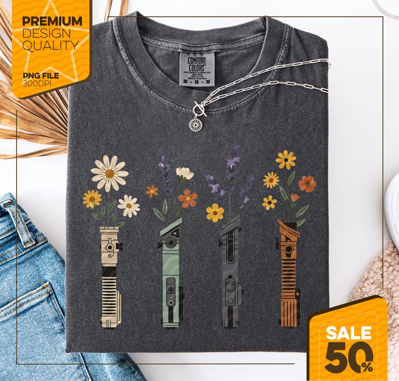 May include: Dark gray t-shirt with a floral design. The design features four stylized lightsabers with flowers blooming from the top. The shirt has the text "Comfort Colors" and "Premium Design Quality". A silver necklace is also visible.