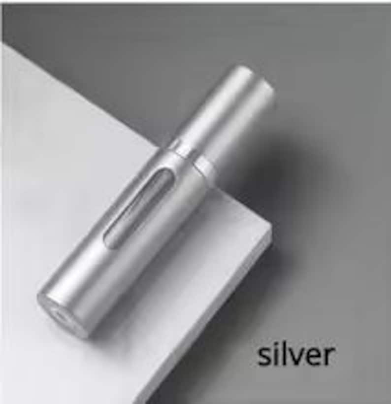 K&ouml;nnte beinhalten: Ein silberner, zylindrischer Parf&uuml;mzerst&auml;uber mit einem transparenten Fenster. Der Metallzerst&auml;uber hat ein schlankes Design. Das Wort "silver" ist unten rechts aufgedruckt. Er ist zur Aufnahme von Parf&uuml;m bestimmt.