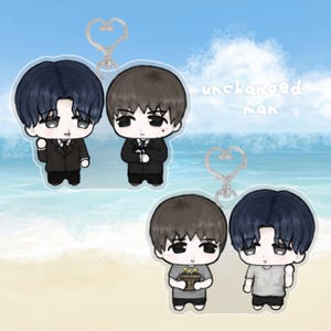 May include: Two acrylic keychains featuring chibi-style characters. The top keychain shows two figures in black suits. The bottom keychain shows two figures in gray shirts, one holding a small potted plant. The text "unchanged man" is visible.