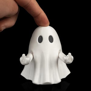 Könnte beinhalten: Eine weiße, 3D-gedruckte Geisterfigur mit einem glatten, abgerundeten Kopf und zwei schwarzen, ovalen Augen. Der Geist hat zwei bewegliche Arme, die nach außen gestreckt sind, wobei jede Hand den Mittelfinger zeigt und eine trotzige Geste macht.
