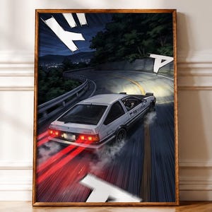 May include: A framed wall art print featuring a white hatchback car drifting on a winding mountain road at night. The car has red taillights, smoke from the tyres, and Japanese text on the side door. The scene uses dynamic manga-style speed lines.