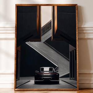 May include: A framed wall art print featuring a dark gray Porsche sports car viewed from the rear, positioned between two large, dark, angular architectural structures with a light-colored, diagonal staircase visible in the background.
