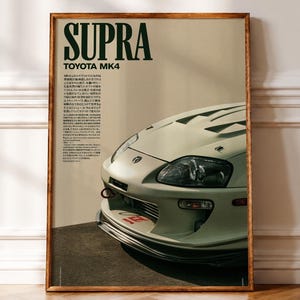 Könnte beinhalten: Ein gerahmtes Poster mit einem hellen Toyota Supra MK4 Sportwagen. Der Text SUPRA und TOYOTA MK4 erscheint in großen dunkelgrünen Buchstaben oben, begleitet von einem japanischen Textblock. Das Auto ist aus einer Front-Viertel-Perspektive zu sehen.
