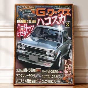 Könnte beinhalten: Ein gerahmtes Magazin-Cover mit dem Titel G-Works, das einen silbernen Oldtimer Nissan Skyline GT-R zeigt. Das Cover enthält japanischen Text, eine kleine Illustration einer Person im Anzug und mehrere kleinere Autobilder.