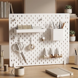 Peut inclure: Un panneau perforé rectangulaire blanc avec une étagère horizontale contenant des stylos, un récipient carré pour les ustensiles d'écriture, des crochets supportant des ciseaux et un rouleau de ruban adhésif, et trois clips tenant des bobines de fil.