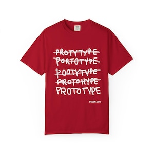 Könnte beinhalten: Rotes T-Shirt mit dem weißen Wort "PROTOTYPE", das mehrfach wiederholt und durchgestrichen wurde. Die Website-Adresse "tecgs.com" ist unten auf dem T-Shirt aufgedruckt.