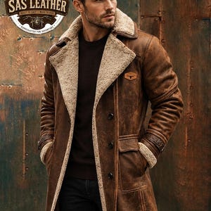 May include: A brown leather coat with a beige shearling lining, featuring a wide lapel, three front buttons, and buckled cuffs. A small leather patch with a bull logo is on the chest. The text SAS LEATHER EST 2019 is visible in the top corner.