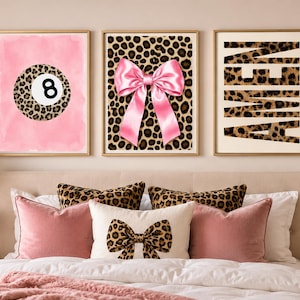 May include: Three framed wall art prints featuring a pink watercolor background with a leopard print eight ball, a leopard print background with a large pink satin bow, and a leopard print background with the word AMEN in bold black letters.