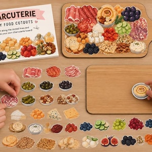May include: A charcuterie play food cutout set featuring a printed instruction sheet, two wooden serving boards, and various paper food items including meats, cheeses, fruits, nuts, and vegetables to assemble on the boards.