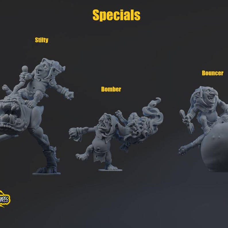 May include: Three grey unpainted resin miniature figures labeled Specials. Stilty is a creature riding a large beast. Bomber is a creature holding a smoking projectile. Bouncer is a creature perched on a large round object. Each figure has distinct features.