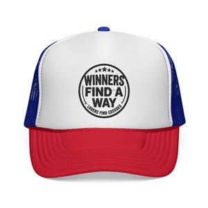 Op de afbeelding: Een truckerpet met een wit voorpaneel, rode klep en blauwe mesh achterkant. De voorkant heeft een zwarte cirkelvormige afbeelding met vijf sterren en de tekst WINNERS FIND A WAY, met de tekst LOSERS FIND EXCUSES onderaan gebogen.