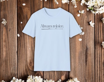 以下が含まれることがあります： 胸元にダークなセリフ体で「Always rejoice.」というテキストがプリントされ、そのすぐ下に細い水平線が引かれた、ライトブルーの半袖Tシャツ。衣服の前面にデザインが施されています。