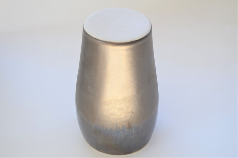 May include: A metallic gold ceramic vase with a white lid. The vase has a smooth, glossy finish and a rounded shape.