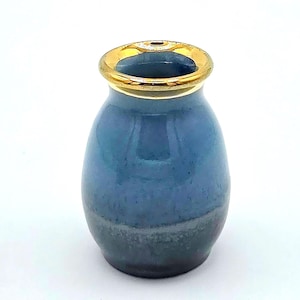 May include: A small, blue ceramic vase with a gold rim. The vase has a rounded shape and a gradient color scheme, transitioning from a lighter blue at the top to a darker blue and gray at the base. The gold rim adds a touch of elegance.