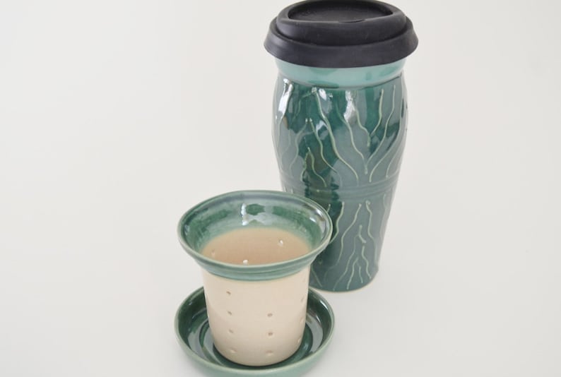 May include: A green ceramic tea infuser with a matching lid and a separate saucer. The infuser has a white interior and a pattern of green lines.