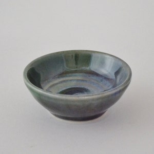 May include: A small, round, green and blue ceramic bowl with a glazed finish.