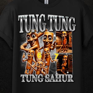 May include: A black short-sleeved t-shirt featuring a graphic print with the text TUNG TUNG TUNG SAHUR. The design includes multiple illustrations of brown, cylindrical, cartoon-like characters with faces, alongside two rectangular photo-style insets.