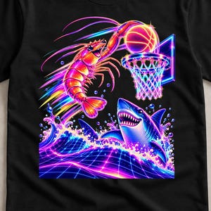 Puede incluir: Una camiseta negra con un gráfico de neón vibrante de un camarón haciendo un mate de baloncesto en una canasta, con un tiburón emergiendo de agua brillante debajo. El diseño utiliza colores brillantes rosa, azul y amarillo sobre un fondo de rejilla.