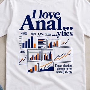Op de afbeelding: Een wit T-shirt met korte mouwen en donkerblauwe tekst met de tekst I love Anal...ytics. De afbeelding bevat diverse staaf- en lijngrafieken met oranje en blauwe accenten, samen met de tekst I'm an absolute demon in the (excel) sheets.