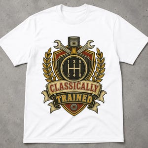 May include: A white short-sleeve t-shirt featuring a graphic of a manual transmission gear shift pattern, a piston, and two crossed wrenches inside a shield emblem with wheat stalks and a banner reading CLASSICALLY TRAINED in red and yellow.
