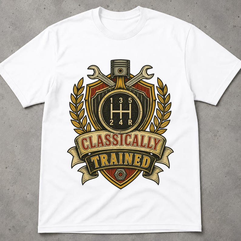 May include: A white short-sleeve t-shirt featuring a graphic of a manual transmission gear shift pattern, a piston, and two crossed wrenches inside a shield emblem with wheat stalks and a banner reading CLASSICALLY TRAINED in red and yellow.