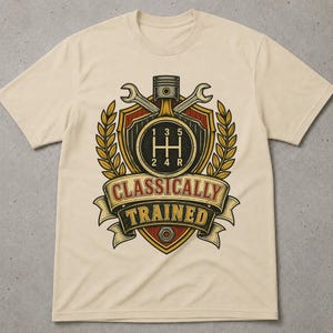 May include: A beige short-sleeved t-shirt featuring a graphic print of a shield, a piston, and two crossed wrenches. The design includes a manual transmission gear shift pattern and a banner with the text "CLASSICALLY TRAINED" in bold lettering.