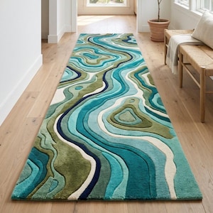May include: A long rectangular runner rug featuring a textured, multi-layered design with flowing, organic lines in shades of teal, turquoise, olive green, and cream. The surface has a carved, three-dimensional appearance with varying pile heights.