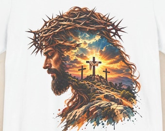 May include: A white short-sleeve t-shirt featuring a graphic print of a profile view of a bearded figure wearing a crown of thorns, with a landscape scene of three crosses on a hill at sunset integrated into the hair and beard area.