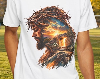 May include: A white short-sleeve t-shirt featuring a graphic print of a profile view of a bearded figure wearing a crown of thorns, with a landscape scene of a sunrise and a stone tomb integrated into the silhouette of the head.