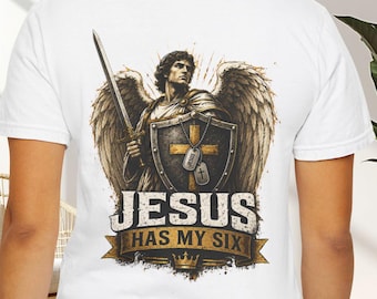 May include: A white t-shirt featuring a graphic on the back of an angel with wings holding a sword and a shield with a cross. Two dog tags hang over the shield. Below the graphic, the text reads JESUS HAS MY SIX on a banner with a crown.